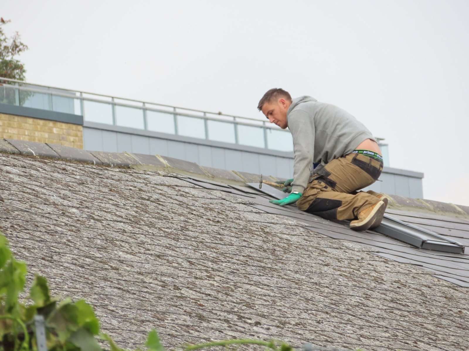 Home Construction worker installing shingles on a rooftop. Outdoor building maintenance.
